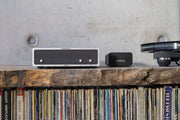 Lindemann Woodnote FONO phonostage and power supply on a shelf above a record collection